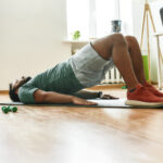 Man performing a glute bridge on a yoga mat—an exercise often used to activate pelvic floor muscles during Kegel routines for men’s sexual and vascular health.