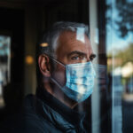 Man wearing a COVID-19 mask—symbolizing ongoing recovery and hidden cardiovascular risks like arterial stiffness and elevated central blood pressure linked to long COVID.